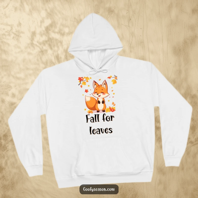 Funny fox character juggling colorful autumn leaves, featured on a warm hoodie, perfect for celebrating fall.
