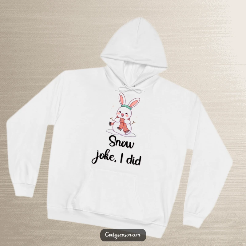 Funny, cozy hoodie showing a happy bunny character adding a scarf to a snowman, spreading winter cheer.