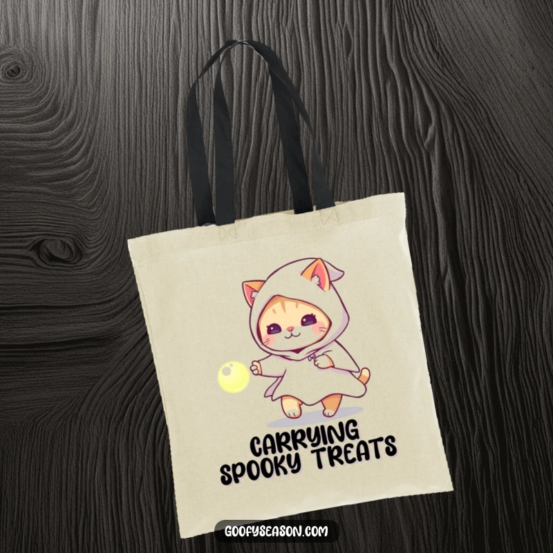 Funny cat with a ghost costume chasing a glowing orb on a tote bag, a practical Halloween accessory.